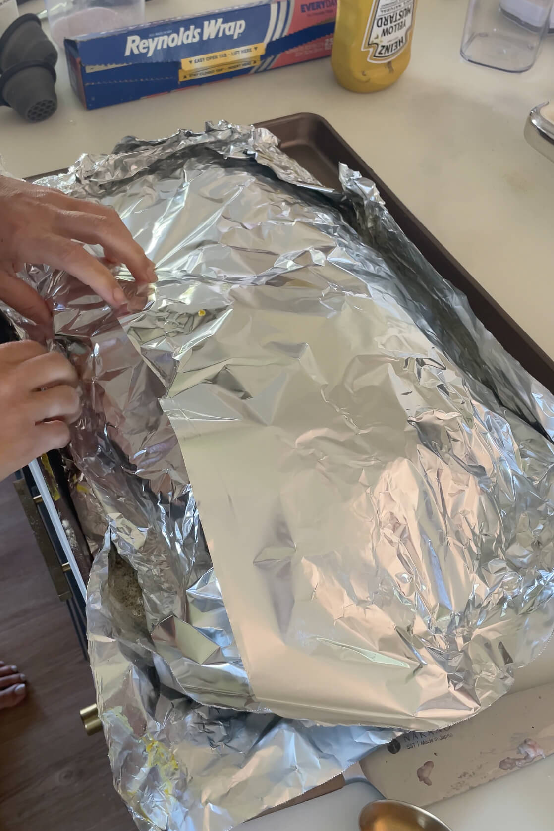Wrapping a brisket with foil before putting it in a smoker.